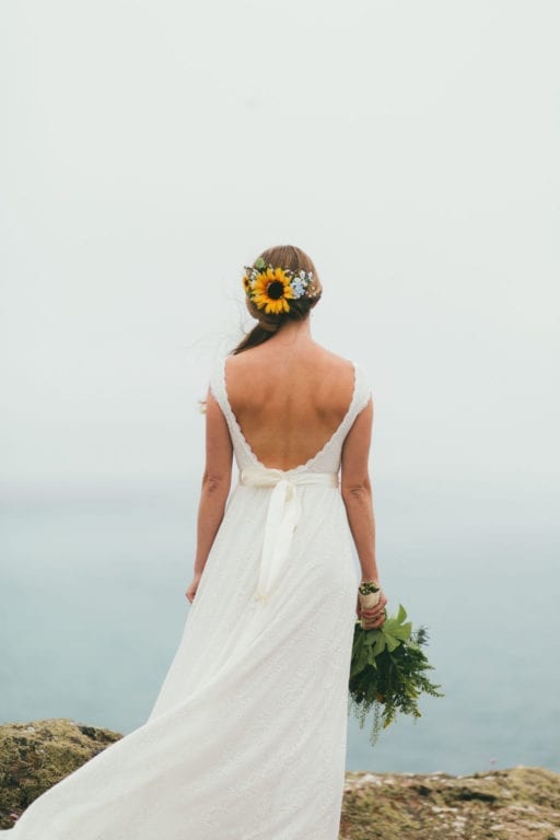 A bride looks over the misty ocean at St Agnes Beacon during her Wild Tipi clifftop wedding. Luckily, she had a wedding weather plan B in place.
